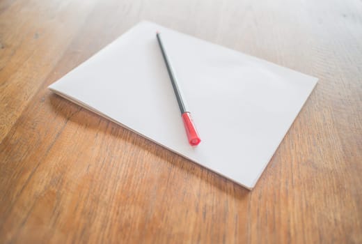 White paper and red pen on wooden table, stock photo