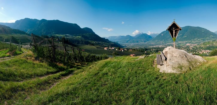Panoramic view above the city of Merano / South Tyrol with cross between apple plantations and view of the opposite Texel Group