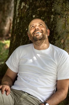 An image of a man with a beard relaxing under a tree