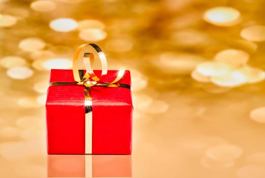 Photo of red and gold gift box with out of focus lights on a golden background
