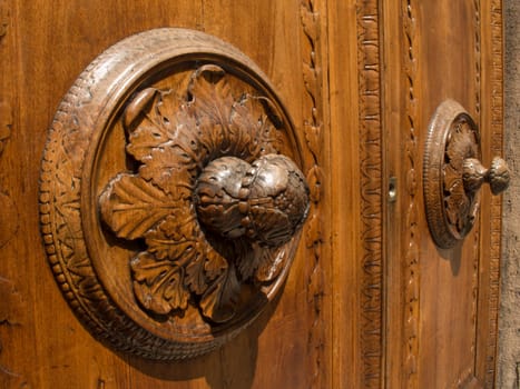 Wooden door in Arezzo in the foreground with a rosette