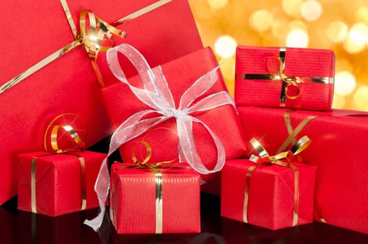 Photo of a collection of red and gold gift boxes with out of focus lights on a golden background
