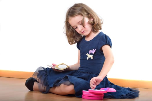 Little cute girl making up while wearing her mother's shoes