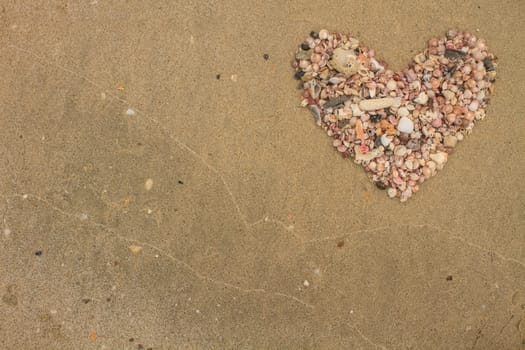 Heart made of sea shells lying on a beach sand in summer