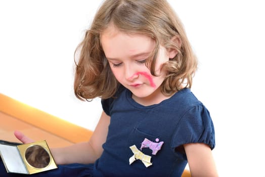 Little cute girl using make-up to turn herself into clown