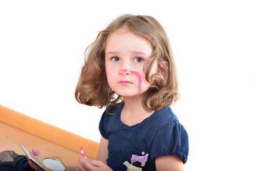 Little cute girl using make-up to turn herself into clown