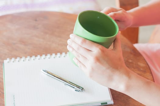 Hand holding green mug in coffee shop, stock photo