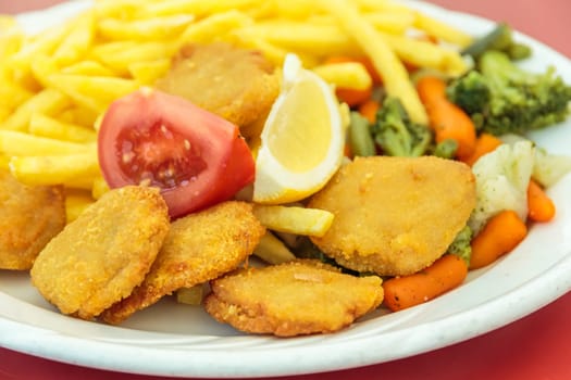 Fried chicken nuggets, French fries, lemon and vegetables