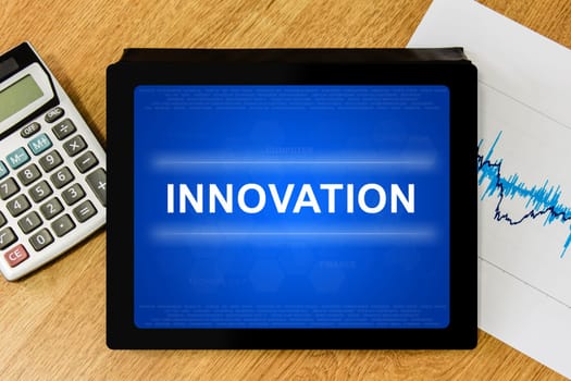 innovation word on digital tablet with calculator and financial graph