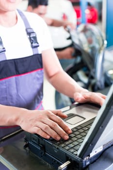 car mechanic checking auto engine with diagnostics tool in his workshop