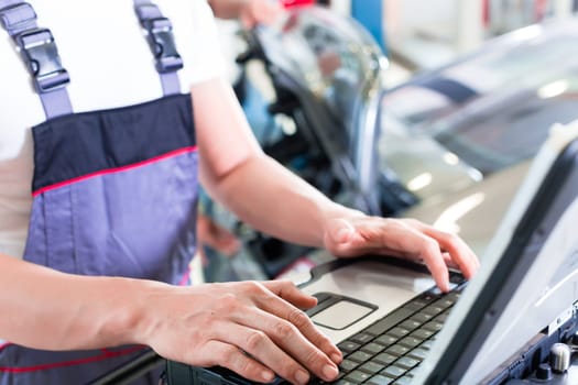 car mechanic checking auto engine with diagnostics tool in his workshop
