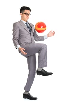 Portrait of full length Asian businessman playing with soccer ball, isolated on white background.