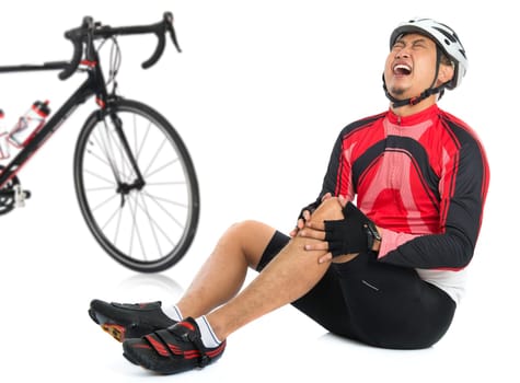 Asian cyclist fell down from bike with injured knee joint, painful facial expression and sitting on floor, isolated on white background.
