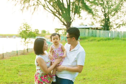 Portrait Of Asian Chinese Family Relaxing In Park Together