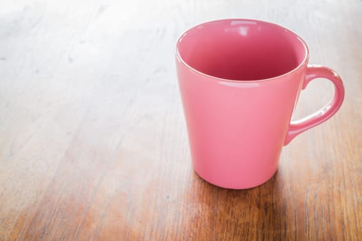 Pink ceramic cup on wooden table, stock photo