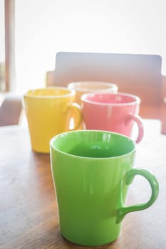 Colorful ceramic coffee cups on wooden table, stock photo