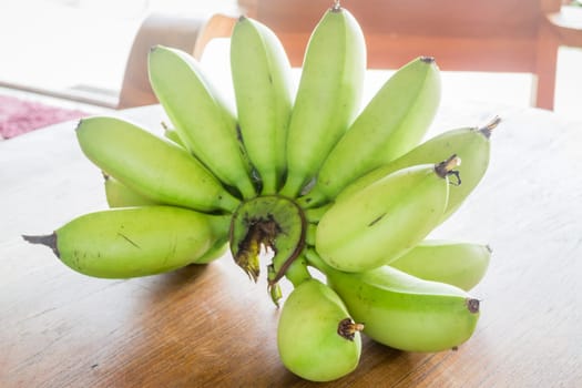 Green banana on wooden table, stock photo