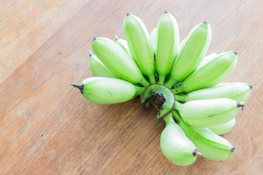 Raw banana bunch on wooden table, stock photo