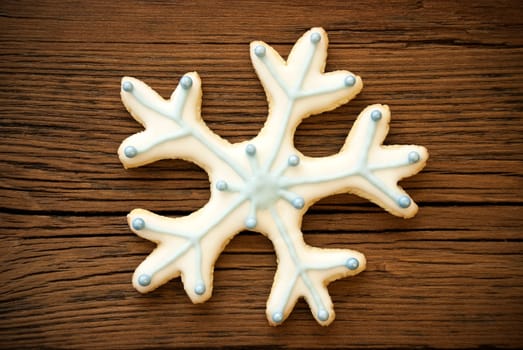 Snowflake Cookie with White and Blue Decoration on Wood
