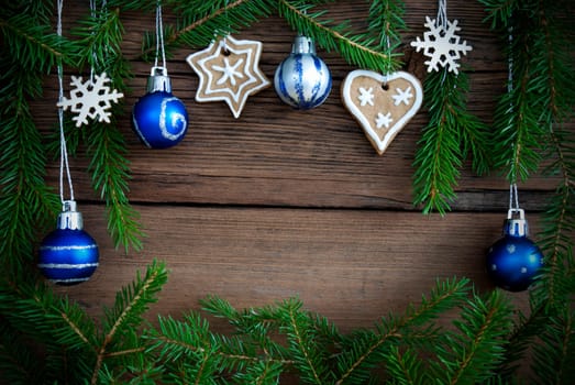 Green Fir Tree Branches Framing Christmas Decorations Hanging on Wooden Background with Copy Space