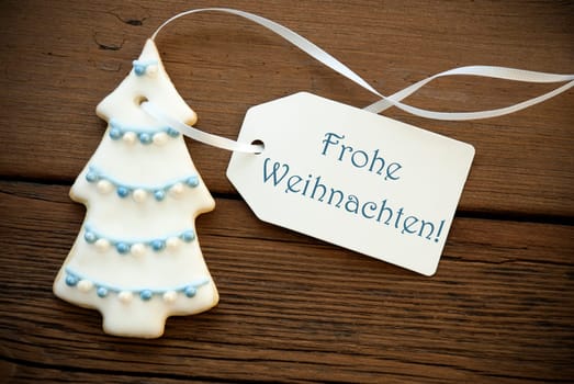 A Blue German Frohe Weihnachten, which means Merry Christmas, on a white Label with a Christmas Tree Cookie