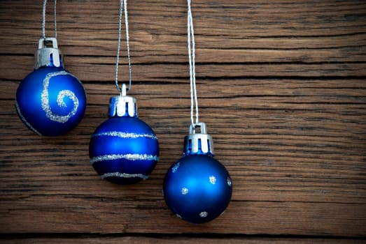 Three Blue Christmas Balls with Silver Decoration Hanging on Wooden Background with Copy Space