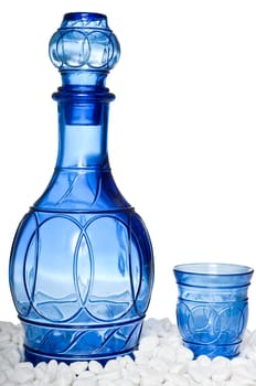 Blue bottle and tumbler on white stones, isolated on a white background