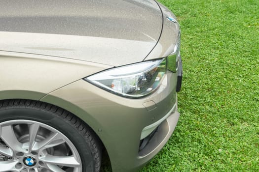 New model of BMW prestigious business car on fresh green grass wet after rain. Close-up details.