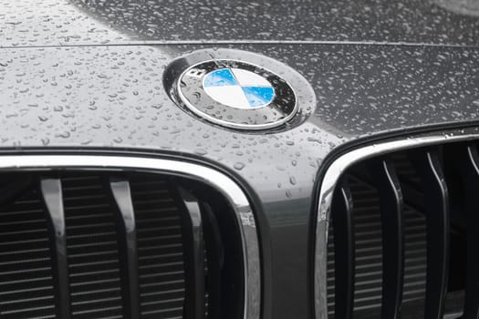 BMW logo on wet surface of hood of new model elite deluxe car. BMW is part of the "German Big 3"" luxury automakers, which are the three best-selling luxury automakers in the world."
