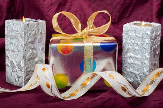 Silver gitf box with silver candles and ribbons on burgundy background