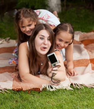 Adult woman and two girls making faces and doing photos at park