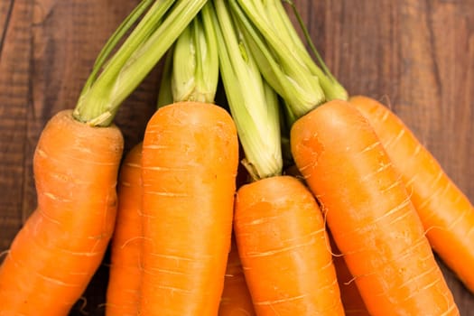 Carrots with green on wood