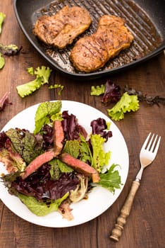 Entrecote in a grill pan and plate with salad