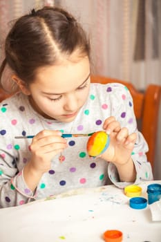 Portrait of little girl painting easter egg with watercolor