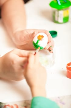 Closeup shot of women and child hands painting easter eggs