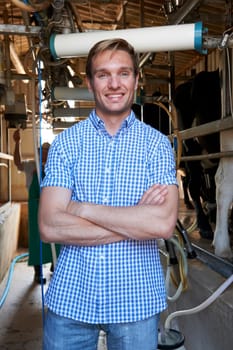 Portrait Of Farmer With Dairy Cattle In Milking Shed