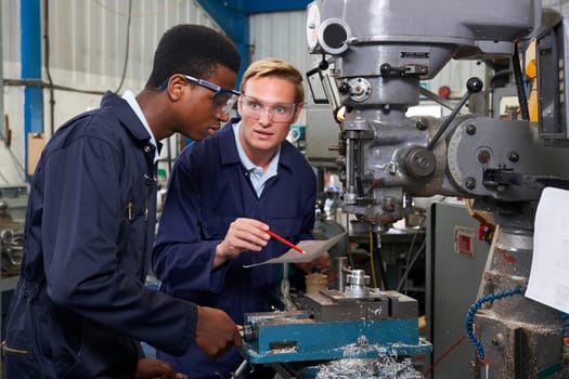 Engineer Showing Apprentice How to Use Drill In Factory