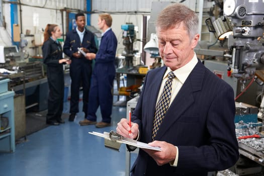 Owner Of Engineering Factory With Staff In Background