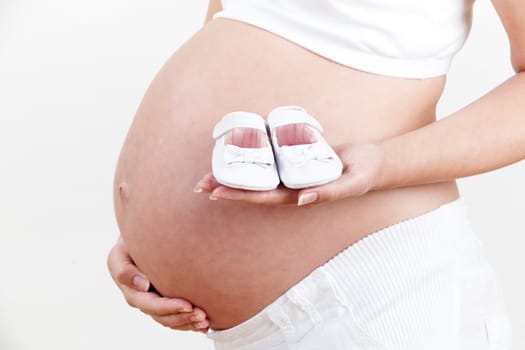 Close Up Of Pregnant Woman Holding Baby Shoes