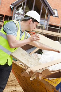 Builder Putting Waste Into Rubbish Skip
