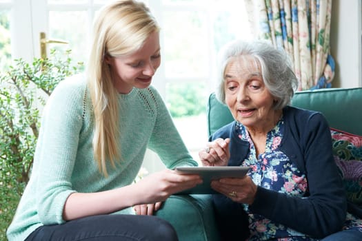 Granddaughter Showing Grandmother How To Use Digital Tablet