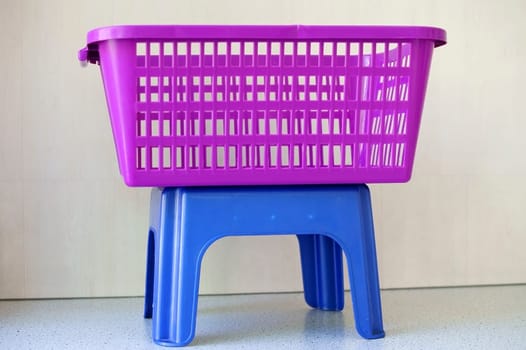 The photograph of a colorful laundry basket on a shelf of a laundromat.