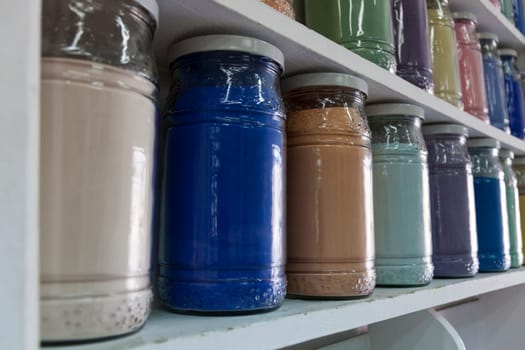 Shelves filled with rows of glasses of colorful pigments in a pharmacy artist's supplies in Marrakech as a close-up