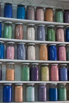 Shelves filled with rows of glasses of colorful pigments in a pharmacy artist's supplies in Marrakech as a close-up