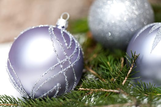 Silver Christmas tree balls in green fir branches with white shiny snow as macro detail