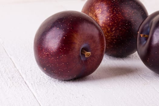 Fresh shiny juicy plums with ripe color with stem up as close-up