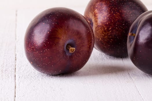Fresh shiny juicy plums with ripe color with stem up as close-up