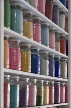 Shelves filled with rows of glasses of colorful pigments in a pharmacy artist's supplies in Marrakech as a close-up