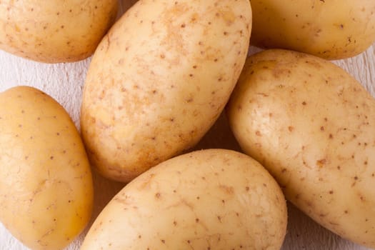 Fresh washed potatoes with peel as a close-up on a rustic wooden board
