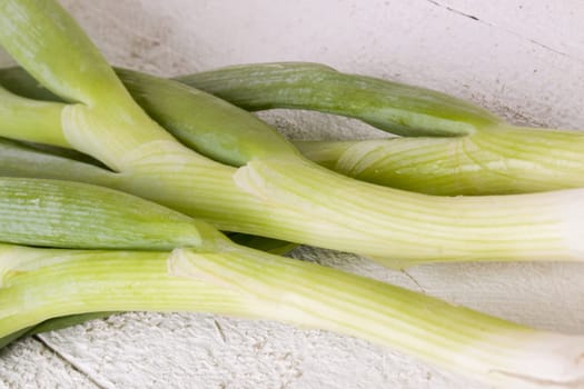 Bunch fresh leek onions spring onions with root on a rustic white wooden board